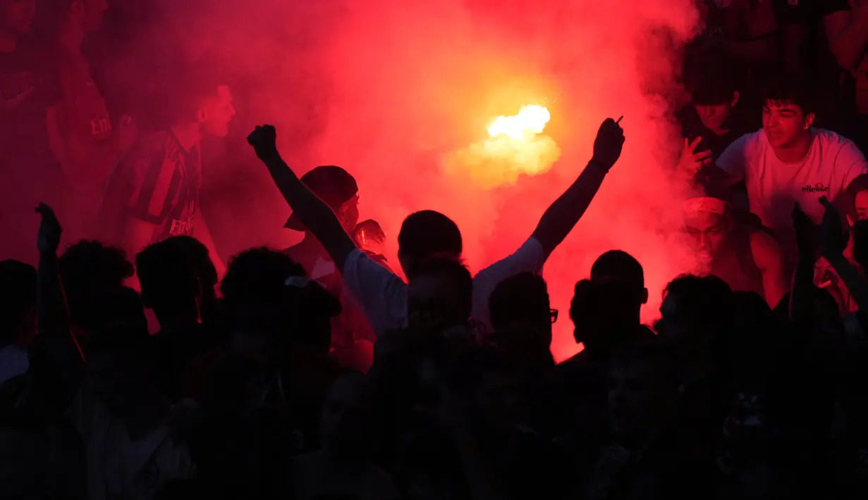 Suporter AC Milan menyalakan suar saat menunggu bus yang membawa para pemain tim sepak bola AC Milan pada parade kemenangan Liga Italia di depan Katedral Gotik Milan, Milan, Italia, 23 Mei 2022. (AP Photo/Luca Bruno)