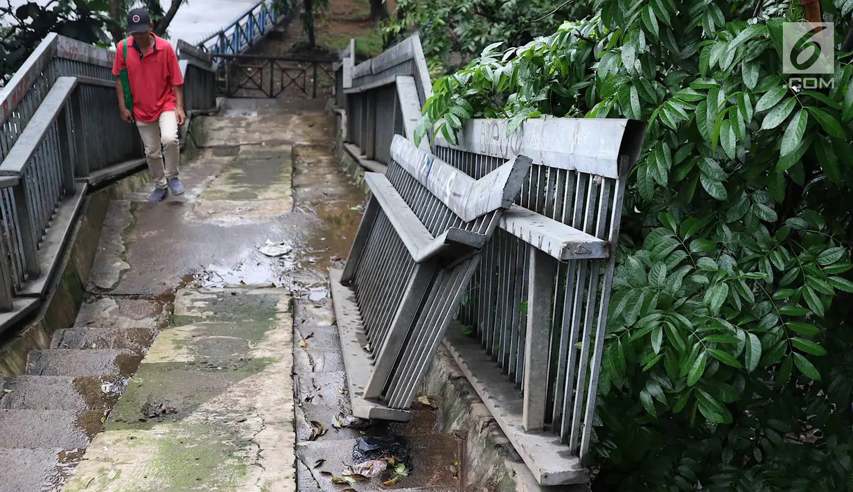 Pejalan kaki menaiki tangga JPO yang rusak di Terminal Kampung Rambutan, Jakarta, Senin (28/1). Kondisi JPO yang sebagian pagar pembatasnya rusak tersebut membahayakan pejalan kaki apabila tidak segera diperbaiki. (Liputan6.com/Immanuel Antonius)