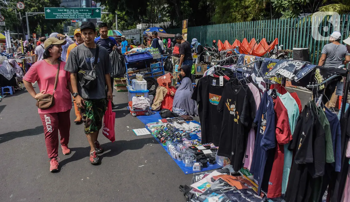 Warga melintasi pedagang kaki lima (PKL) yang berjualan di kawasan Jalan Sumenep, Jakarta, Minggu (17/11/2019). Jalan Sumenep dan Jalan Pamekasan merupakan titik yang sudah ditentukan untuk berjualan saat car free day (CFD). (Liputan6.com/Faizal Fanani)
