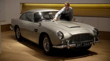 Seorang staf berpose dengan Aston Martin DB5 yang digunakan dalam film James Bond GoldenEye tahun 1995 di rumah lelang Bonham, London, Selasa (19/6). Mobil legendaris yang dikemudikan aktor Pierce Brosnan itu bakal dilelang pemiliknya. (AP/Matt Dunham)