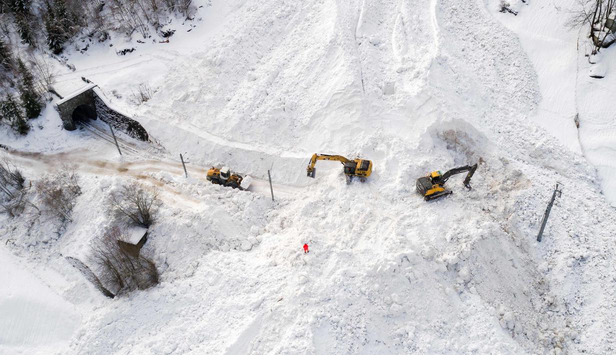 Ekskavator dikerahkan untuk memulihkan jalur kereta api antara Visp dan Taesch yang terputus akibat longsoran salju, Swiss, (10/1). Bencana tersebut menyebabkan terputusnya jalur kereta api dan seluruh akses menuju Zermatt. (AFP Photo/Fabrice Coffrini)