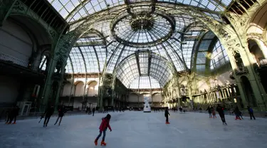 Orang-orang  berseluncur di arena ice skating di bawah kubah kaca mewah legendaris, Grand Palais, Paris, Senin (17/12). Arena ice skating musiman ini terbuka untuk umum selama liburan Natal. (AP Photo/Christophe Ena)