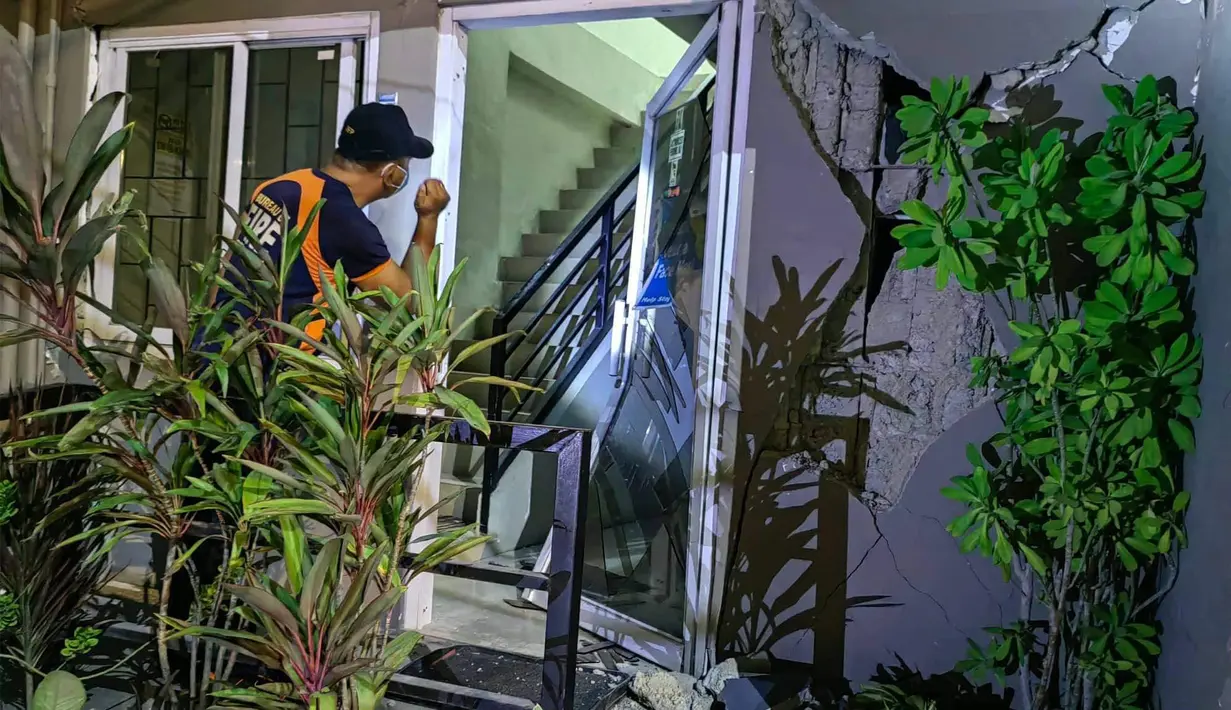 seorang petugas melakukan inspeksi terhadap bangunan yang rusak di kota Batac, Ilocos Norte pada 25 Oktober 2022, setelah gempa berkekuatan 6,4 melanda Filipina utara.  (Photo by Handout / Bureau of Fire Protection / AFP)