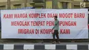 Salah satu pencari suaka melintasi spanduk penolakan di depan bekas Markas Kodim di Kalideres, Jakarta, Selasa (16/7/2019). Sebelumnya, para pencari suaka dari berbagai negara berkonfilk ini tinggal di pinggir jalan dan trotoar di kawasan Kebon Sirih, Jakarta. (Liputan6.com/Helmi Fithriansyah)