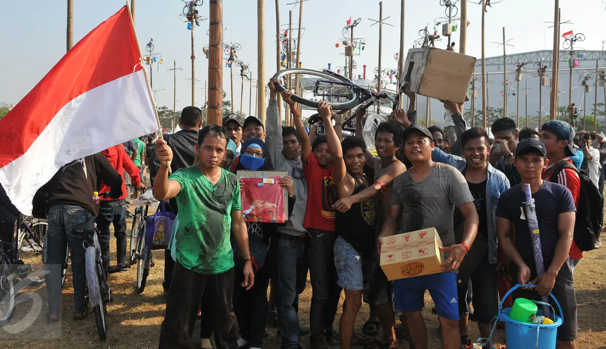 Sejumlah warga berhasil mengambil hadiah pada lomba Panjat Pinang Kolosal dalam rangka merayakan HUT RI ke-70 di Pantai Karnaval, Ancol, Jakarta, Senin (17/8). Sebanyak 124 batang pinang disediakan dengan beragam hadiah. (Liputan6.com/Herman Zakharia)