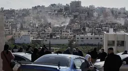 Penghancuran ini bagian dari operasi "Iron Wall" (Tembok Besi) yang telah berlangsung selama hampir satu tahun sejak awal 2025, menargetkan kamp pengungsi di Jenin, Tulkarm, dan Nur Shams di Tepi Barat. Tampak dalam foto, warga menyaksikan buldoser tentara Israel merobohkan rumah-rumah di kamp pengungsi perkotaan Palestina Nur Shams, dekat kota Tulkarem di Tepi Barat, Rabu 31 Desember 2025. (AP Photo/Majdi Mohammed)