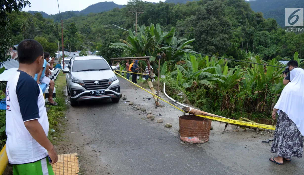 Kendaraan melintas dekat lokasi jalan longsor di Desa Bondawuna, Kabupaten Bone Bolango, Gorontalo, Selasa (30/4/2019). Hujan yang mengguyur wilayah Kabupaten Bone Bolango mengakibatkan empat desa di Kecamatan Suwawa Selatan, dan Bulango Timur Bone Bolango banjir. (Liputan6.com/Arfandi Ibrahim)