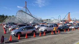 Orang-orang duduk di dalam mobil mereka di area observasi untuk memeriksa kemungkinan efek samping setelah mendapatkan suntikan vaksin di pusat vaksinasi Covid 19 skala besar yang didirikan di Six Flags Magic Mountain di Valencia, California, Selasa (2/2/2021). (VALERIE MACON/AFP)