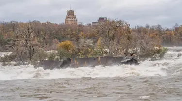 Gambar pada 1 November 2019, sebuah kapal yang tertancap di bebatuan atas Air Terjun Niagara selama lebih dari seabad telah bergeser di sungai St Lawrence, di Ontario, Kanada.  Pejabat taman nasional Air Terjun Niagara menyebutkan kapal bergerak karena cuaca buruk. (Chris Giles/Niagara Parks via AP)