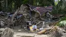 Kerusakan juga terjadi pada fasilitas umum lainnya, seperti jembatan dan akses jalan, yang mengganggu mobilitas dan menyebabkan beberapa wilayah terisolasi sementara. Tampak dalam foto, warga desa duduk di luar rumah mereka yang rusak akibat banjir bandang di Garoga, Provinsi Sumatera Utara, pada Kamis 4 Desember 2025. (YT HARIONO/AFP)