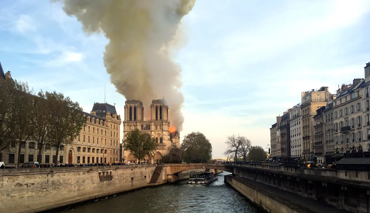 Kebakaran melanda bangunan Gereja Katedral Notre Dame di pusat kota Paris, Prancis, pada Senin (15/4). Kebakaran yang terjadi dengan cepat menghancurkan dua menara persegi katedral, dan mengepulkan asap hitam pekat ke angkasa. (AP Photo/Lori Hinnant)