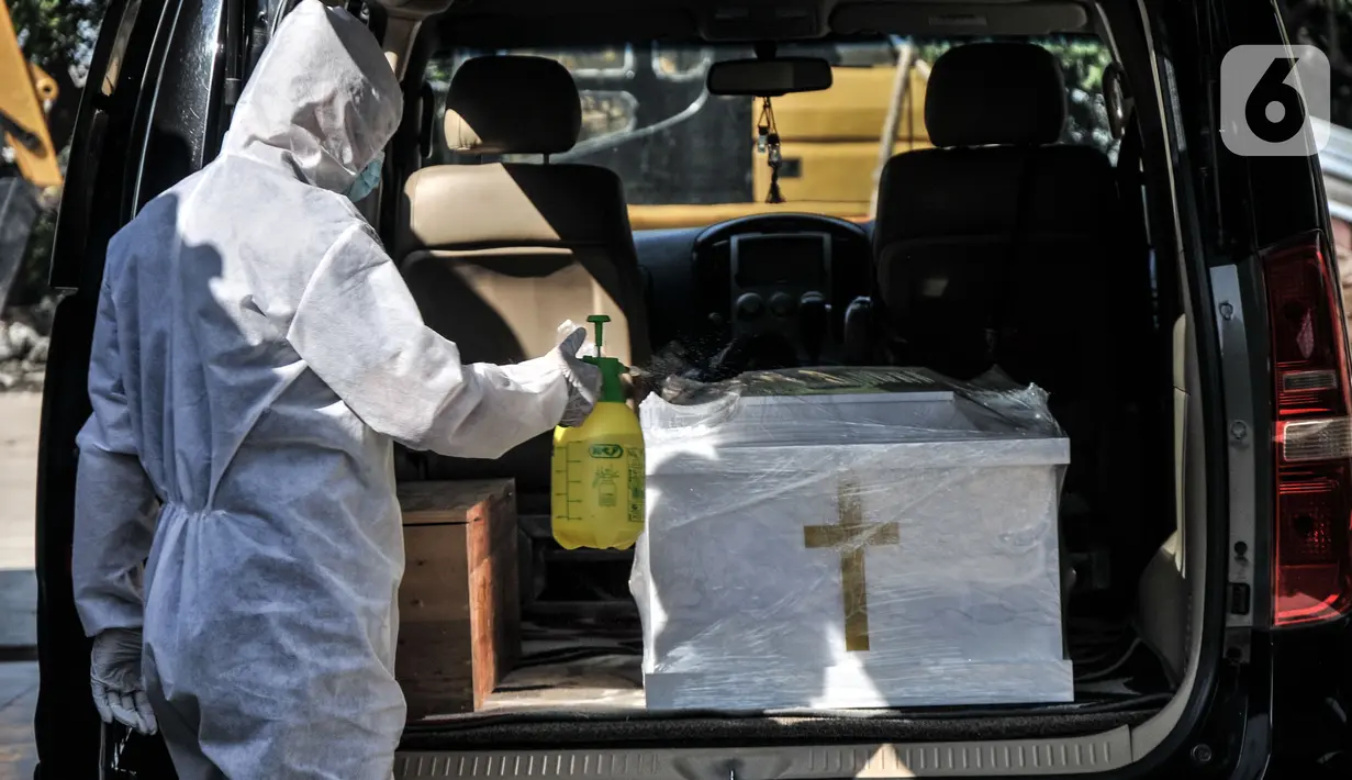 Petugas menyemprotkan disinfektan pada peti jenazah pasien Covid-19 sebelum proses kremasi di Krematorium Cilincing, Jakarta Utara, Minggu (25/7/2021). Setiap harinya petugas mampu melakukan kremasi sebanyak 11 hingga 14 jenazah di tujuh tungku pembakaran yang tersedia. (merdeka.com/Iqbal S Nugroho)