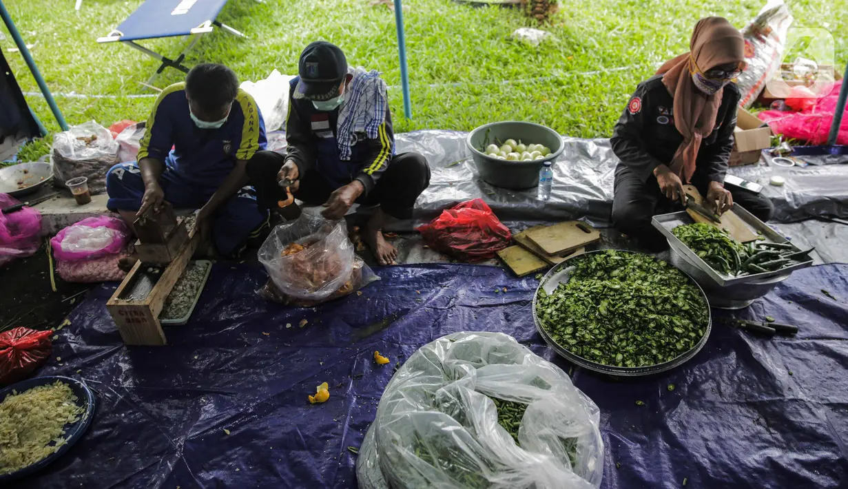Petugas Taruna Siaga Bencana (Tagana) menyiapkan masakan di Dapur Umum Kementerian Sosial Peduli Dampak Covid-19 di Kompleks Gedung Konvensi TMP Nasional-Utama, Kalibata, Jakarta, Rabu (8/4/2020). Dalam sehari, petugas menyiapkan 5.000 hingga 9.000 paket nasi bungkus. (Liputan6.com/Faizal Fanani)