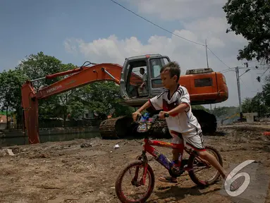 Seorang bocah bersepeda asyik memperhatikan pengerukan Kali Sidang, Jakarta, Jumat (19/9/2014) (Liputan6.com/Faizal Fanani)