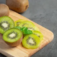 Buah kiwi utuh dan yang sudah dipotong di atas talenan (Foto Dok: Freepik/jcomp).