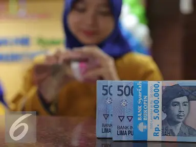 Teller menghitung uang rupiah di Bank Bukopin Syariah, Jakarta, Selasa (29/12). Rupiah kembali melemah, di tengah sepinya transaksi jelang libur Tahun Baru Hingga akhir pekan, pergerakan rupiah diperkirakan masih terbatas. (Liputan6.com/Angga Yuniar)