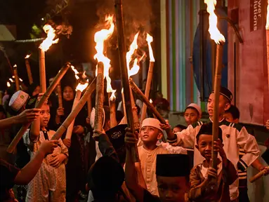 Sejumlah anak-anak mengambil bagian dalam pawai obor pada malam Idul Fitri 1446 Hijriah, yang menandai berakhirnya bulan puasa Ramadan, di Surabaya pada 30 Maret 2025. (JUNI KRISWANTO/AFP)
