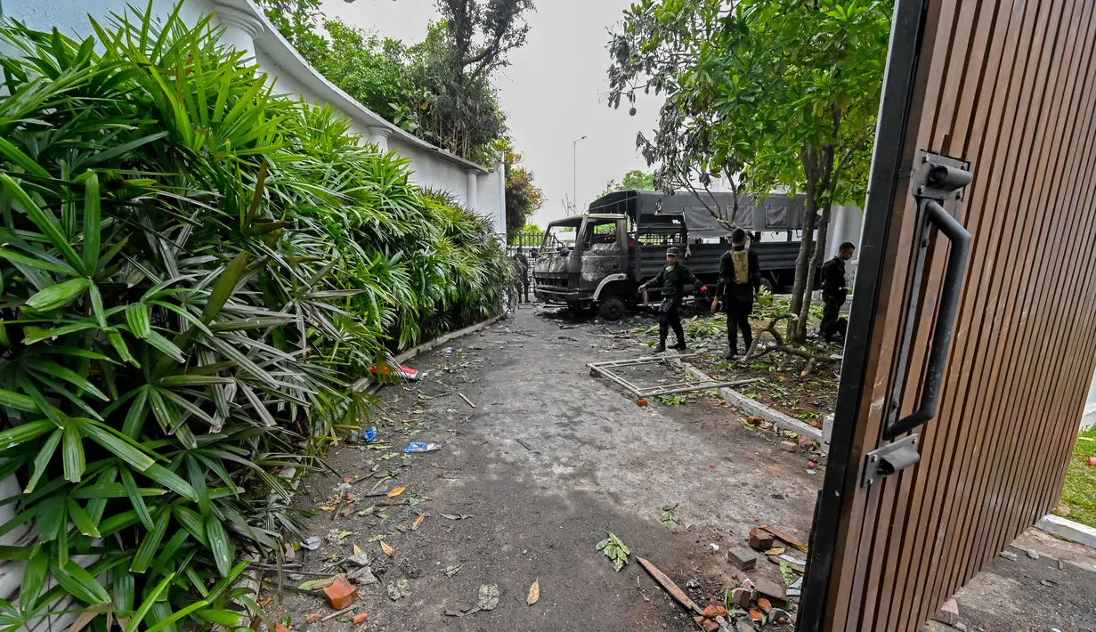 <p>Tentara berjaga di samping sisa-sisa truk yang hangus, sehari setelah dibakar oleh pengunjuk rasa di pintu masuk kediaman resmi Perdana Menteri Mahinda Rajapaksa 'Temple Trees', sehari setelah diterobos oleh para pengunjuk rasa di Kolombo pada 10 Mei 2022. PM Sri Lanka Mahinda Rajapaksa mengundurkan diri di tengah gelombang demonstrasi massal yang memprotes cara pemerintah menangani krisis ekonomi. (ISHARA S. KODIKARA / AFP)</p>