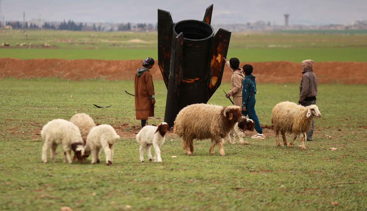 Sejumlah warga lokal nekat melihat dari dekat rudal buatan Iran yang gagal meledak tersebut. Tampak dalam foto, para penggembala, dengan mempertaruhkan diri menghadapi bahaya amunisi yang belum meledak, memeriksa sebuah proyektil rudal Iran yang mendarat di lapangan terbuka di pinggiran Qamishli, Suriah timur, Rabu 4 Maret 2026. (AP Photo/Baderkhan Ahmad)