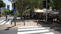 Warga Israel duduk di sebuah kedai kopi luar ruangan di Tel Aviv, Rabu (27/5/2020). Setelah lebih dari dua bulan ditutup untuk membendung penularan virus corona, restoran hingga kafe di Israel diizinkan dibuka kembali hari Rabu, 27 Mei. (AP Photo/Sebastian Scheiner)