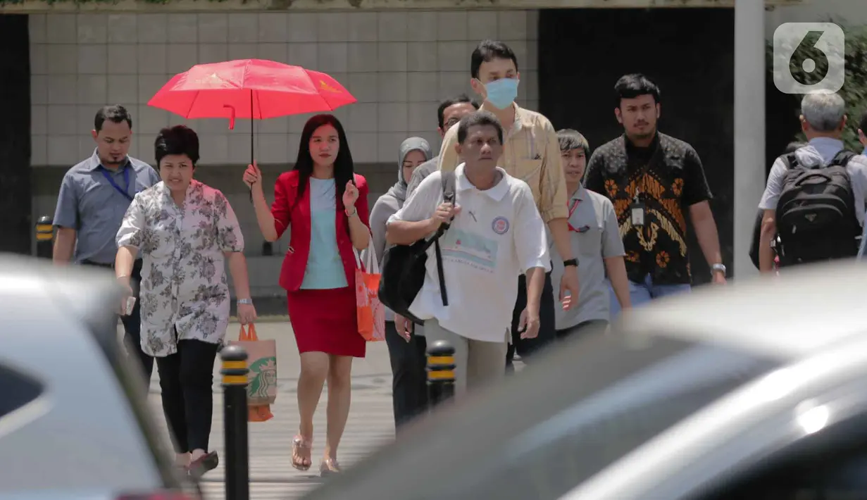 Seorang wanita menggunakan payung menyebrang selama gelombang panas di Jakarta, Selasa (22/10/2019).  BMKG memprediksi wilayah Indonesia akan mengalami panas selama kurang lebih satu minggu ini. Hal ini dikarenakan matahari yang berada dekat dengan jalur khatulistiwa. (Liputan6.com/Faizal Fanani)