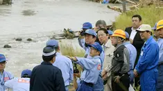 PM Shinzo Abe mendengarkan penjelasan petugas saat mengunjungi wilayah barat daya Jepang yang hancur akibat longsor dan banjir, Rabu (12/7). Abe berjanji pemerintah akan membantu pembangunan kembali di daerah itu segera. (Nozomi Endo/Kyodo News via AP)