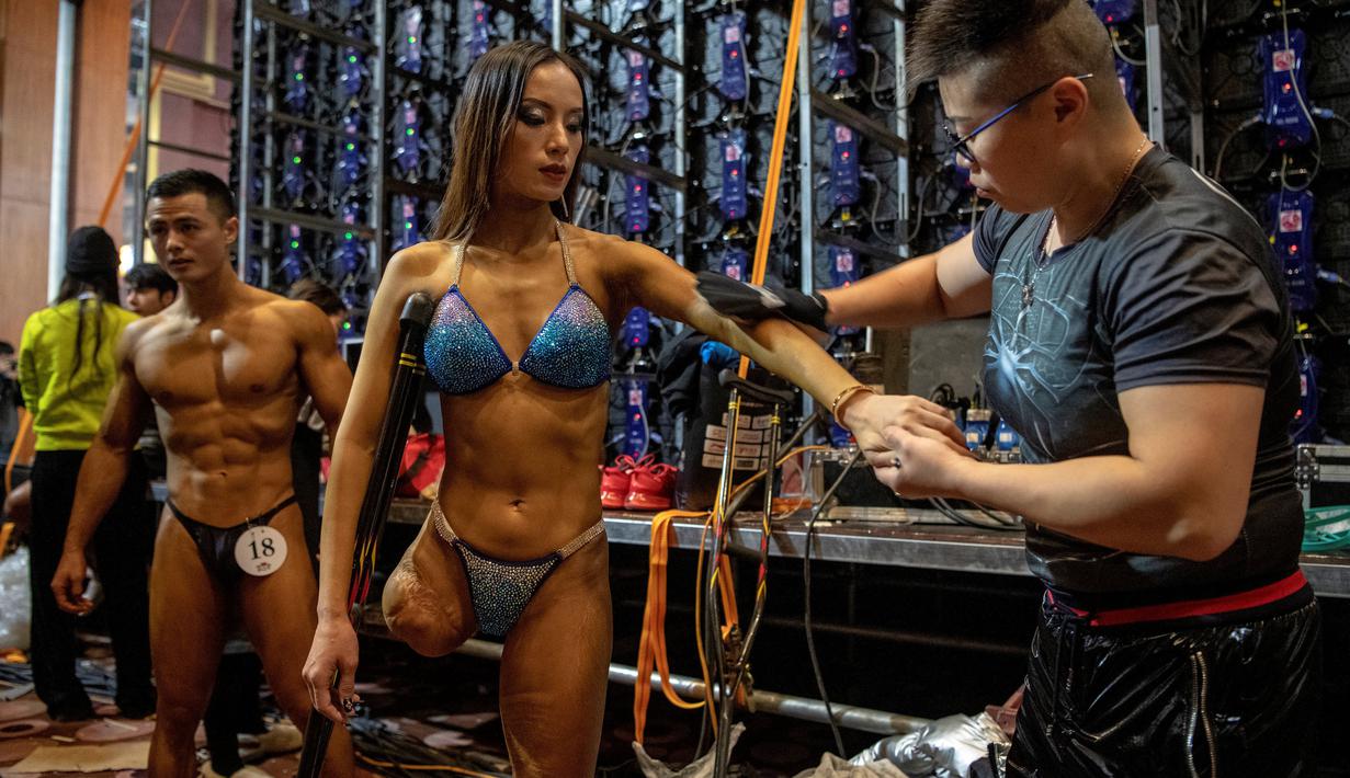 Atlet Binaraga asal China, Gui Yuna (tengah) mendapatkan perawatan dari pelatih sebelum memulai pertandingan dalam ajang International Weightlifting Federation (IWF) Beijing 2020 di Beijing, China, Jumat (11/12/2020). (AFP/NOEL CELIS)