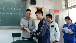 Pengawas mengidentifikasi peserta ujian masuk perguruan tinggi di Handan, Provinsi Hebei, China, (6/6). Melalui simulasi ini dapat diketahui bahwa peserta ujian harus melewati beberapa pemeriksaan sebelum memasuki ruangan. (AFP/STR)