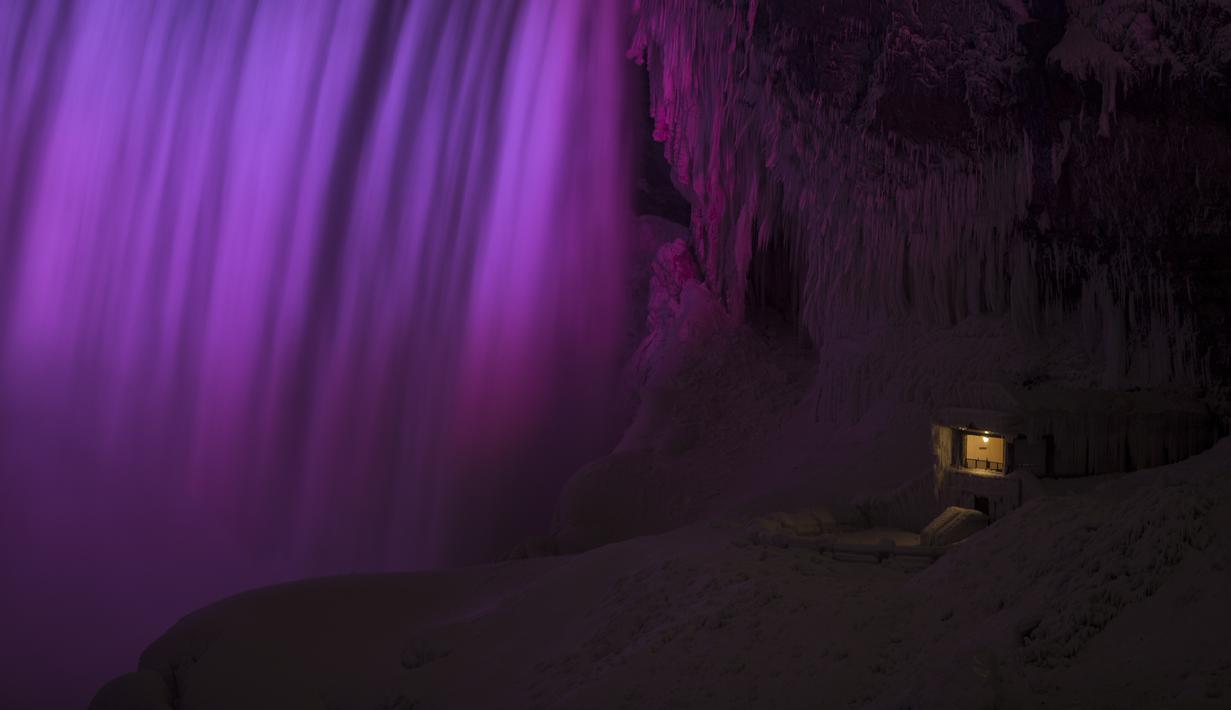 Sorotan lampu mempercantik Air Terjun Niagara yang membeku akibat cuaca dingin ekstrem melanda Ontario, Kanada, Senin (9/1). Bagi para pengunjung, bekunya air terjun yang memisahkan dua negara itu jadi tontonan menarik. (Geoff Robins/AFP)