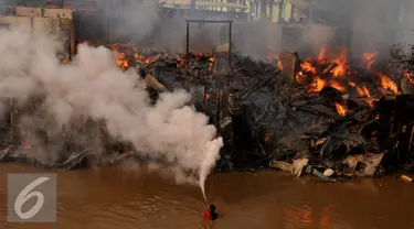 Seorang warga menyemprotkan alat pemadam api saat terjadinya kebakaran di bantaran sungai Ciliwung, Jakarta, Rabu (2/9/2015). Penyebab kebakaran tersebut belum di ketahui. (Liputan6.com/Johan Tallo)