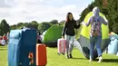 Dua wanita memindahkan tenda mereka ketika mengantre untuk membeli tiket pada hari pertama turnamen tenis Kejuaraan Wimbledon 2019 di The All England Tennis Club di Wimbledon, London barat daya (1/7/2019). Turnamen ini dimulai 1 Juli-14 Juli 2019. (AFP Photo/Ben Stansall)