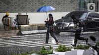 Pejalan kaki yang menggunakan payung saat hujan deras menyeberang jalan di kawasan Thamrin, Jakarta, Rabu (23/11/2022). Kepala Pelaksana Badan Penanggulangan Bencana Daerah (BPBD) DKI Jakarta Isnawa Adji mengimbau masyarakat untuk mengurangi aktivitas di luar rumah apabila Jakarta mengalami cuaca ekstrem. (Liputan6.com/Faizal Fanani)