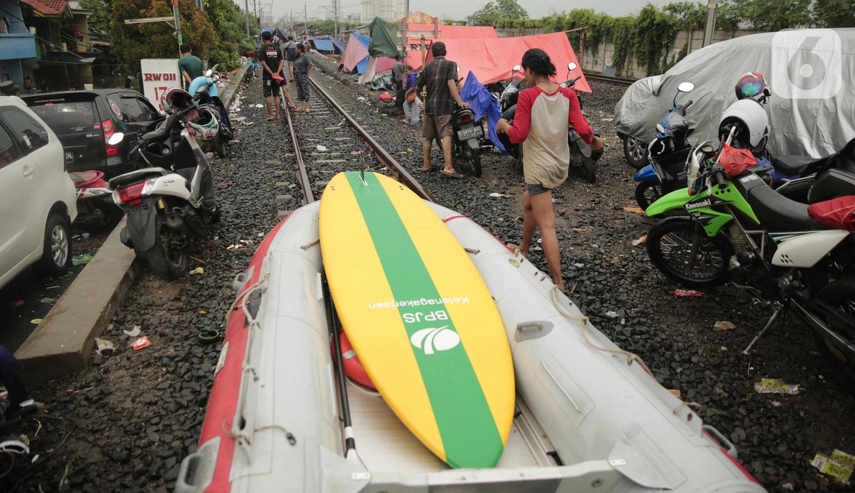 Perahu karet dan tenda pengungsi banjir terlihat di jalur rel kereta commuterline Tangerang-Duri di Kembangan Baru, Jakarta, Jumat (3/1/2020). Jalur rel yang nonaktif sementara karena banjir dimanfaatkan warga untuk mendirikan tenda darurat karena rumah mereka terendam. (Liputan6.com/Faizal Fanani)