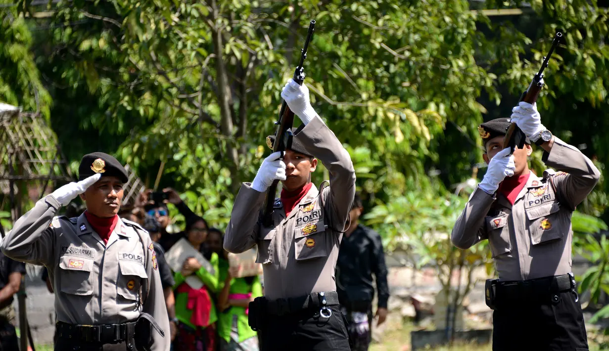 Petugas melepas tembakan salvo ke udara saat upacara pemakaman Aipda Wayan Sudarsa, polisi korban pembunuhan pasangan bule, Bali, Minggu (21/8). Prosesi secara institusi Polri itu dilakukan sebelum jenazah dibakar sesuai adat Hindu. (SONNY Tumbelaka/AFP)