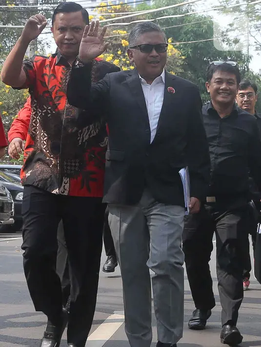 Hasto terlihat mengenakan setelan jas warna abu-abu melambaikan tangan ke hadapan awak media. (Liputan6.com/Herman Zakharia)