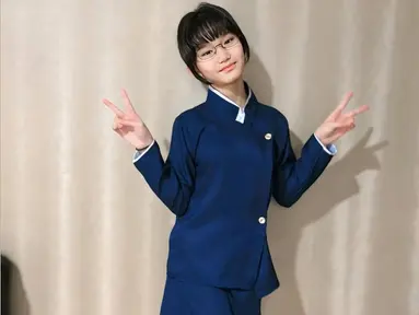 Atasan yang dikenakan Bilqis memiliki desain asimetris dengan kancing emas yang memberikan sentuhan elegan. Kerah putih tinggi semakin memperkuat kesan khas Jepang, dipadukan dengan celana panjang biru tua yang serasi. Rambut pendek berponi serta kacamata yang dikenakannya membuatnya semakin mirip karakter dalam anime atau drama Jepang. (Liputan6.com/IG/@ayutingting92)