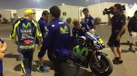 Pebalap Movistar Yamaha, Valentino Rossi (bertopi kuning), memandangi motor YZR-M1 miliknya setelah crash pada hari kedua tes MotoGP 2017 di Sirkuit Losail, Qatar, Sabtu (11/3/2017). (Bola.com/Twitter/izaskunruiz)