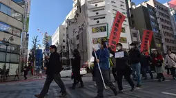 Sekelompok pria Jepang membawa spanduk sambil meneriakkan berbagai yel saat menggelar demonstrasi anti-Valentine di Tokyo, Minggu (12/1). Para pria tersebut mengklaim, pasangan yang merayakan hari Valentine melukai hati mereka. (KAZUHIRO NOGI/AFP)