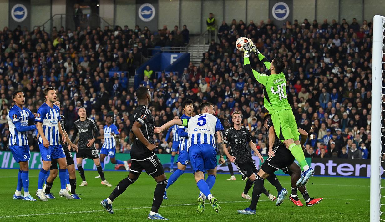Kiper Ajax Amsterdam, Diant Ramaj (kanan) berusaha mengamankan bola pada laga Grup B Liga Europa 2023/2024 melawan Brighton di American Express Community Stadium, Brighton, Inggris, Jumat (27/10/2023) dini hari WIB. Laga dimenangkan Brighton dengan skor 2-0. (AFP/Glyn Kirk)