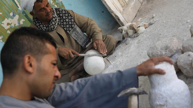 Para pemahat bekerja di sebuah bengkel kerajinan alabaster atau sejenis batu pualam di Desa Gurna, Luxor, Mesir, 17 Desember 2020. Desa Gurna terkenal sebagai penghasil kerajinan tangan dan suvenir bergaya Mesir kuno yang dibuat dari pahatan alabaster. (Xinhua/Ahmed Gomaa)