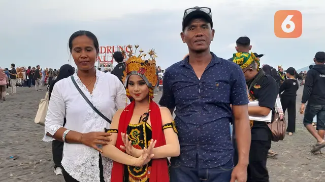 Triwahyuni (Kanan) bersama suaminya Agung (kiri)  mendampingi putrinya Shela Noviana (Tenga0 yang menajdi salah satu ribuan penari gandrung dalam festival; Gandurng sewu 2022 di Banyuwangi (Hermawan Arifianto/Liputan6.com)