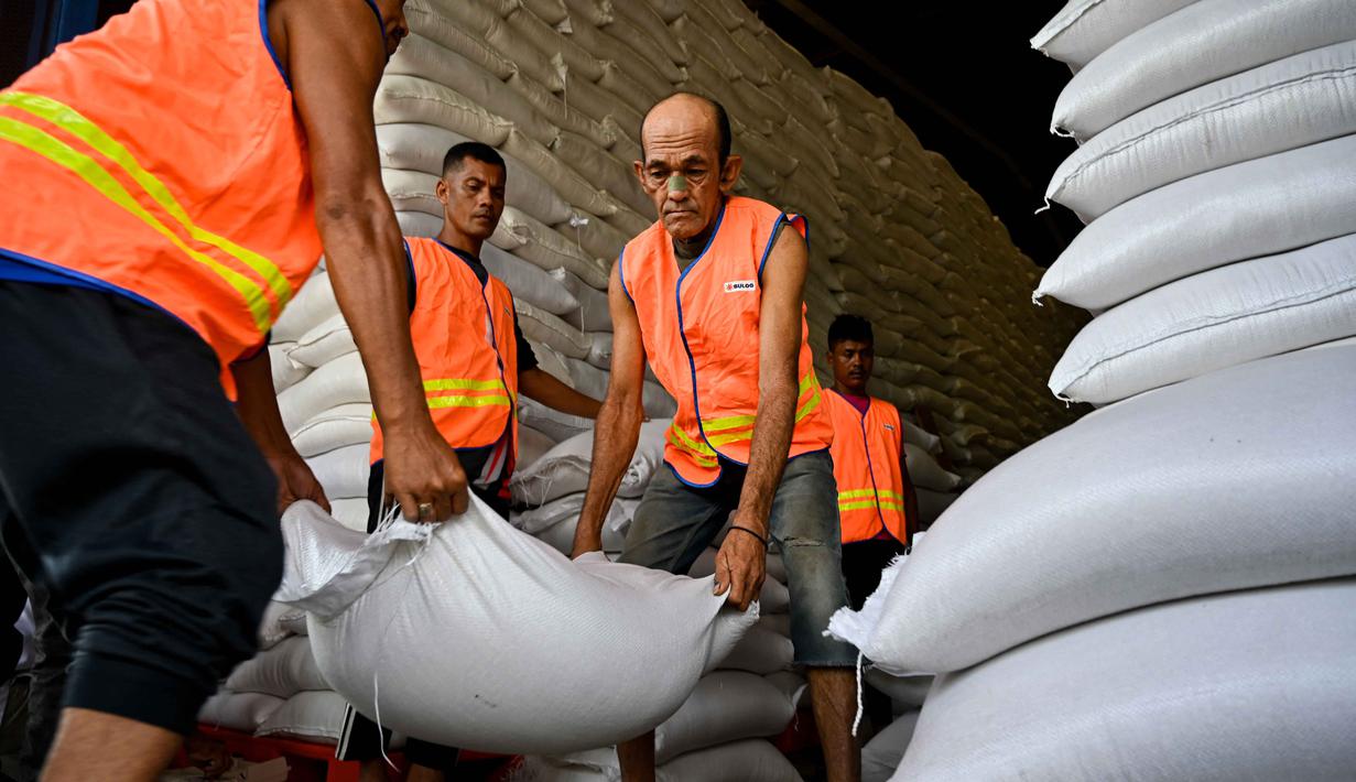 Ketersediaan stok beras ini sebagai bentuk dukungan terhadap penanganan bencana, khususnya di provinsi-provinsi yang rawan terdampak. Tampak dalam foto, para pekerja membongkar karung-karung beras di gudang Badan Urusan Logistik (Bulog) di Lambaro, Provinsi Aceh pada 29 Desember 2025. (CHAIDEER MAHYUDDIN/AFP)