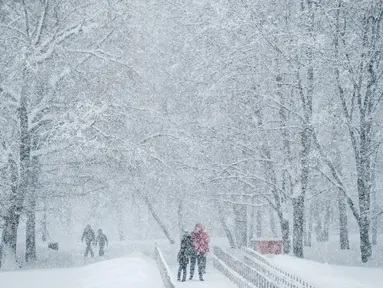 Orang-orang berjalan saat hujan salju turun lebat di dekat museum Kolomenskoye di Moskow (4/2). Hujan salju lebat yang turun semalaman mengakibatkan jalan-jalan dan bangunan di pusat kota dan beberapa daerah di Rusia tertutup salju. (AFP/Yuri Kadobnov)
