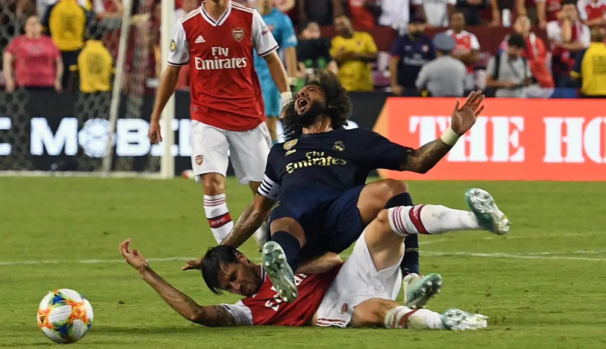 Bek Real Madrid, Marcelo berteriak saat dilanggar bek Arsenal, Carl Jenkinson selama pertandingan International Champions Cup (ICC) 2019 di FedExField, Landover, Maryland (24/7/2019). Madrid menang adu penalti atas Arsenal 3-2 (2-2). (AFP Photo/Jim Watson)