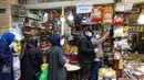 Pedagang mengenakan masker wajah dan sarung tangan lateks, karena pandemi virus corona COVID-19, melayani pembeli selama bulan suci Ramadan di pasar Tajrish, Taheran, Iran (25/4/2020). (AFP/Atta Kenare)