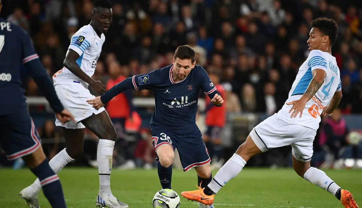 Penyerang Paris Saint-Germain (PSG) Lionel Messi (tengah) berebut bola dengan bek Olympique Marseille Boubacar Kamara pada laga Liga Prancis pekan ke-32 di Parc des Princes, Senin (18/4/2022) dini hari WIB. PSG vs Marseille berakhir dengan skor 2-1. (FRANCK FIFE / AFP)