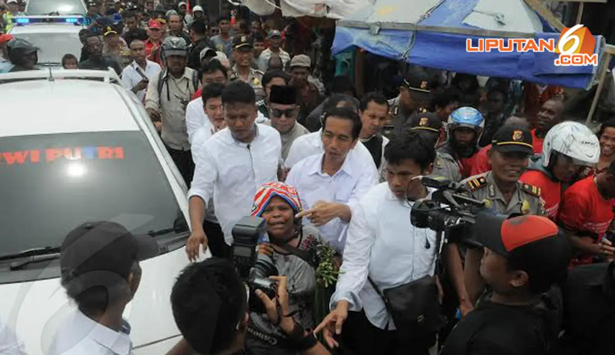 Kunjungan Jokowi ke Pasar Yotefa merupakan bagian dari kampanye PDIP di Papua. Tampak Jokowi meminta seorang nenek untuk melihat ke arah kamera sebelum berfoto bersama (Liputan6.com/Herman Zakharia)