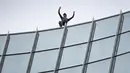 Pendaki kota Prancis, Alain Robert, yang dikenal sebagai "French Spiderman", mengangkat tangannya setelah memanjat gedung Skyper setinggi 153,8 m di Frankfurt am Main, Sabtu (28/9/2019). (AFP Photo/Daniel Roland)