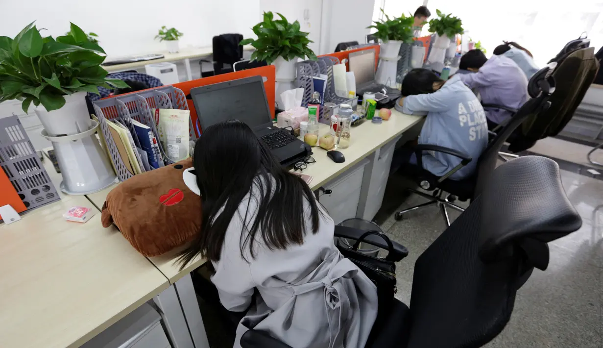 Sejumlah pegawai saat tidur siang di mejanya masing-masing pada jam istirahat di kantornya, di Beijing, China, (21/4). Kegiatan tidur siang ini pemandangan biasa di kalangan pekerja kantoran di China. (REUTERS / Jason Lee)