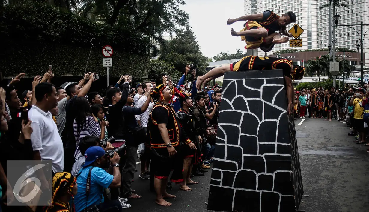 Seorang pria berbaring dan pria lainnya melompat diatasnya saat melakukan lompat batu dalam sebuah acara pagelaran seni dan kebudayaan Nias di Jalan Imam Bonjol, Jakarta, Minggu (12/2). (Liputan6.com/Faizal Fanani)